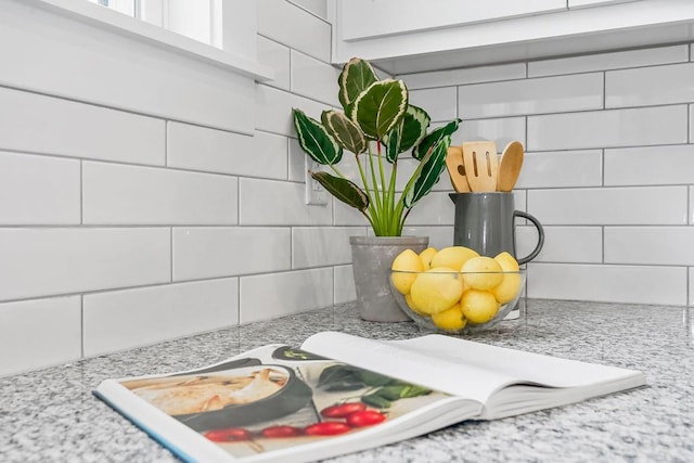 details featuring white cabinets, tasteful backsplash, and light stone counters