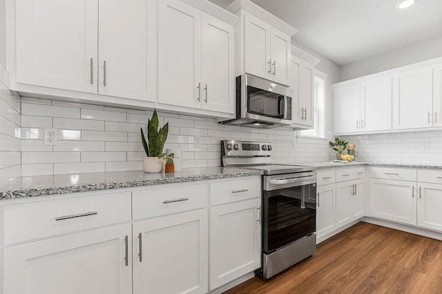 kitchen featuring light stone counters, dark wood finished floors, white cabinetry, stainless steel appliances, and decorative backsplash