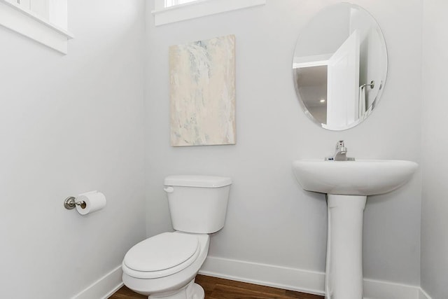 half bath featuring baseboards, toilet, and wood finished floors