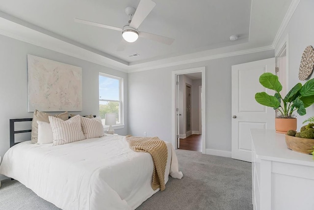 carpeted bedroom with crown molding, a ceiling fan, baseboards, and a raised ceiling