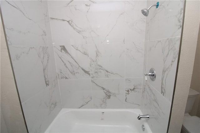 bathroom featuring toilet and tiled shower / bath