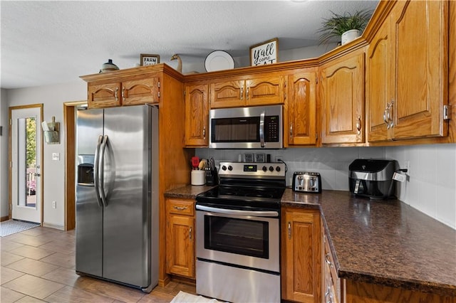 kitchen featuring a textured ceiling, stainless steel appliances, and tasteful backsplash