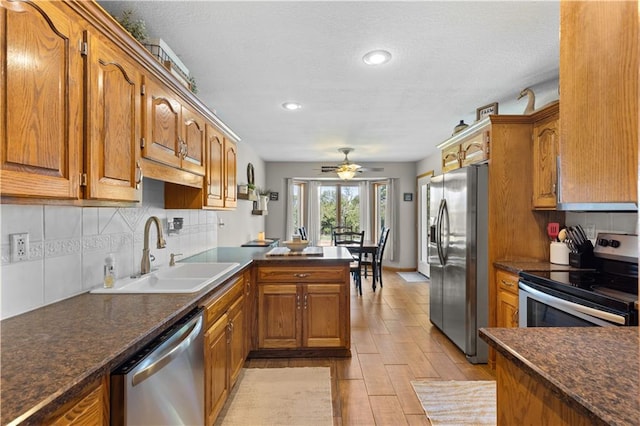 kitchen featuring ceiling fan, decorative backsplash, sink, kitchen peninsula, and appliances with stainless steel finishes