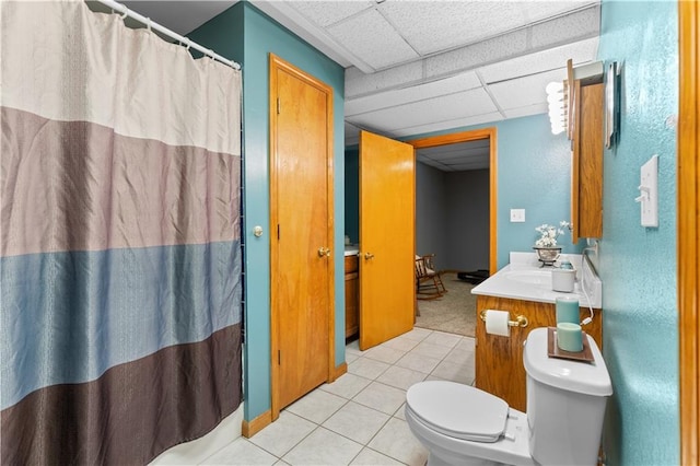 bathroom with tile patterned flooring, a paneled ceiling, vanity, and toilet