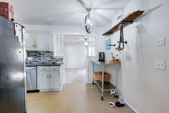 kitchen featuring white cabinetry, stainless steel appliances, ceiling fan with notable chandelier, and backsplash