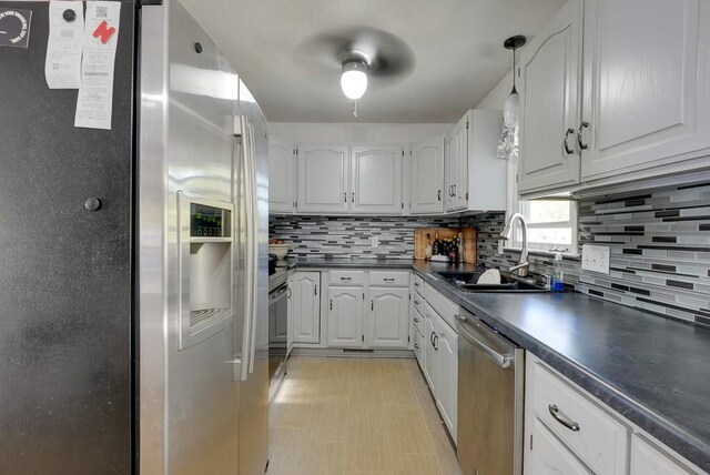 1101 Williams St, Excelsior Springs, MO 64024 - kitchen with appliances with stainless steel finishes, a sink, dark countertops, white cabinetry, and tasteful backsplash