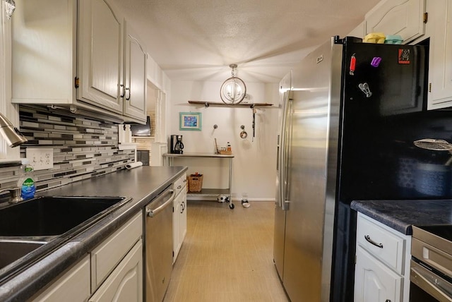 kitchen with a chandelier, white cabinets, stainless steel appliances, and backsplash