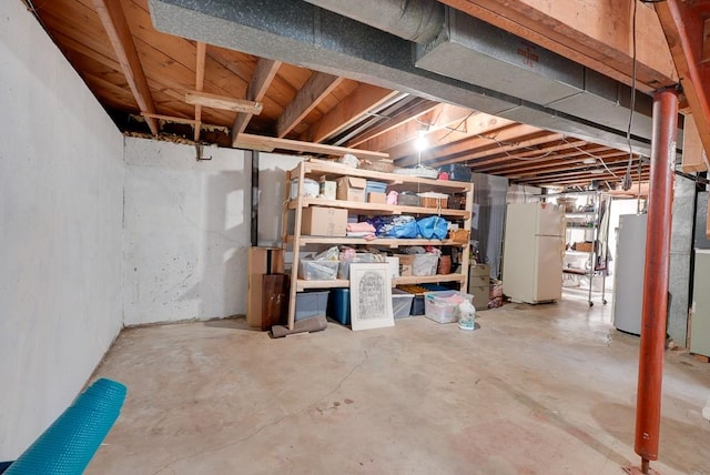 basement featuring water heater and white fridge