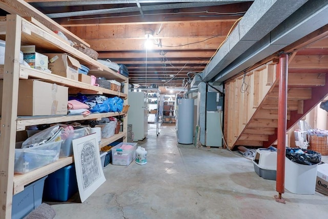 basement featuring gas water heater, heating unit, and white refrigerator