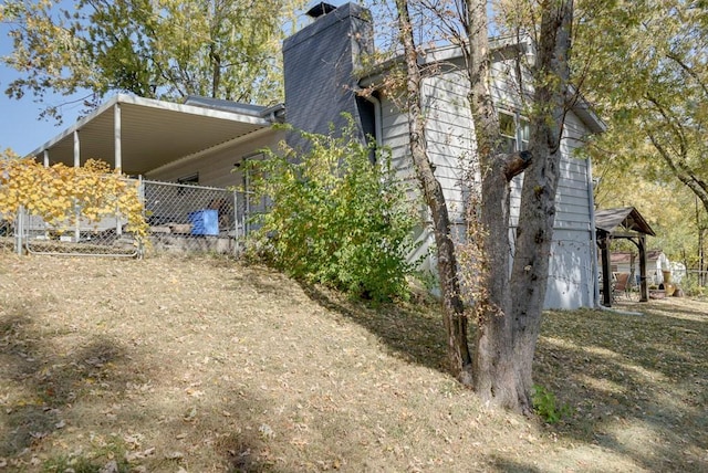 1101 Williams St, Excelsior Springs, MO 64024 - view of side of property featuring a chimney and a carport