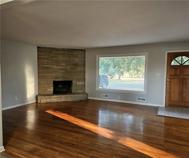 unfurnished living room featuring a fireplace, dark hardwood / wood-style flooring, and plenty of natural light