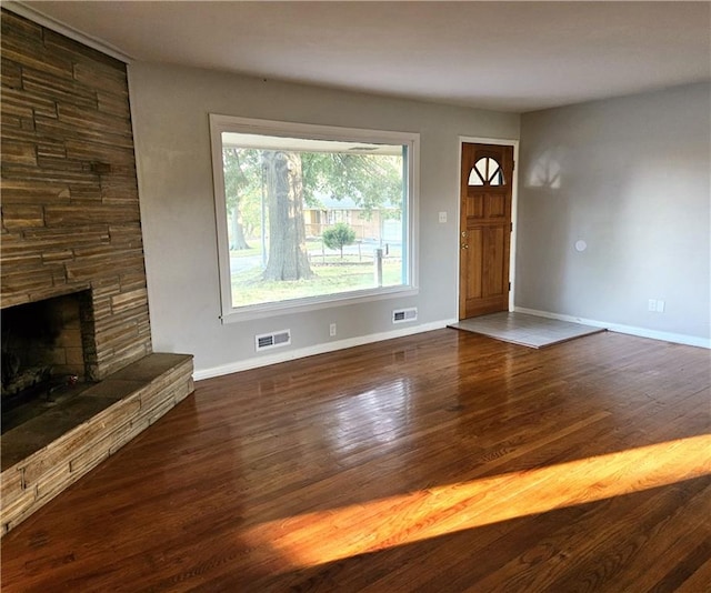 foyer entrance featuring dark hardwood / wood-style floors and a stone fireplace