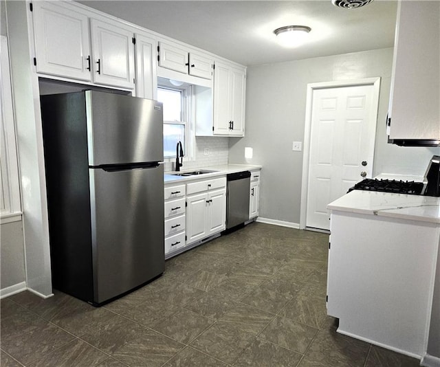 kitchen featuring light stone countertops, sink, stainless steel appliances, backsplash, and white cabinets