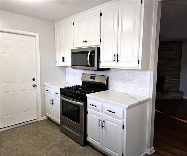 kitchen with light stone counters, white cabinetry, appliances with stainless steel finishes, and tasteful backsplash