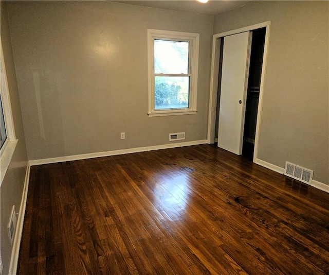 unfurnished bedroom featuring dark hardwood / wood-style floors and a closet