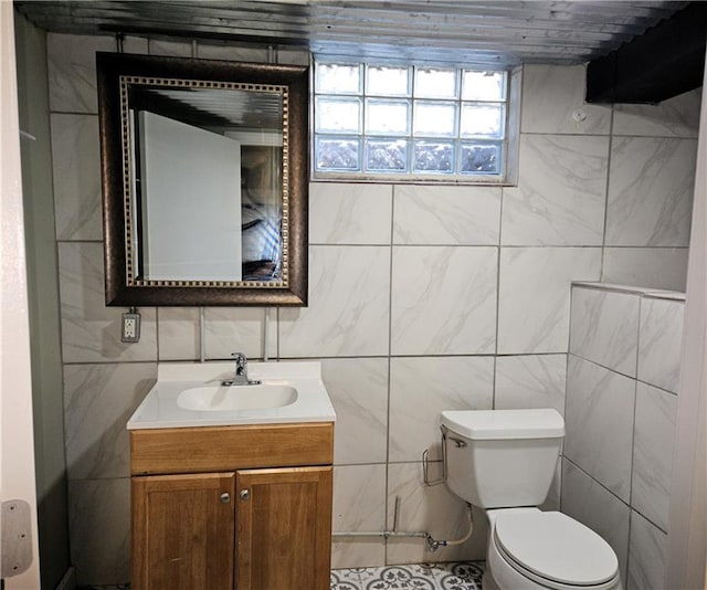 bathroom featuring vanity, toilet, and tile walls