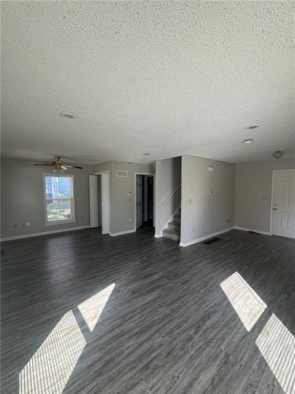 unfurnished living room with a textured ceiling, dark wood-type flooring, and ceiling fan