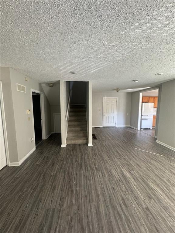 unfurnished living room with a textured ceiling and dark hardwood / wood-style floors