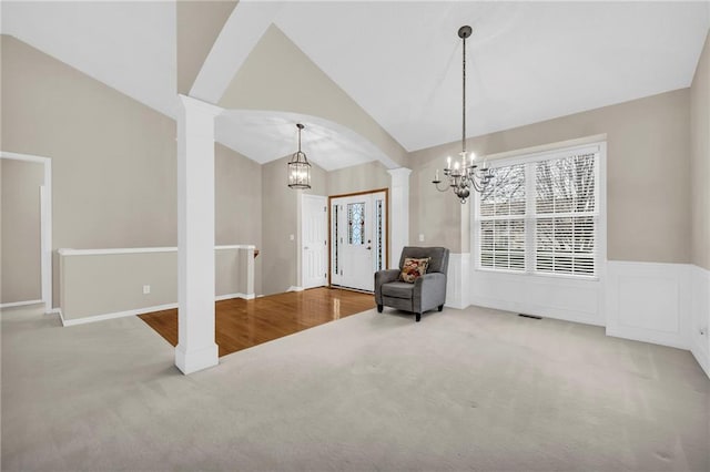 sitting room with carpet flooring, a chandelier, ornate columns, and vaulted ceiling