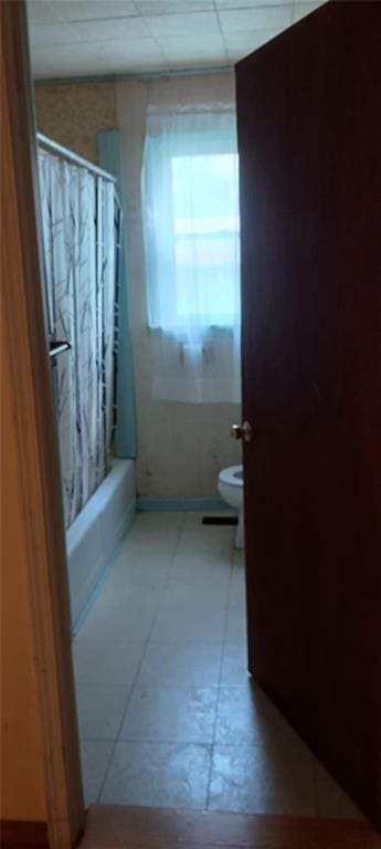 bathroom with shower / bath combination with curtain, a paneled ceiling, toilet, and tile patterned floors