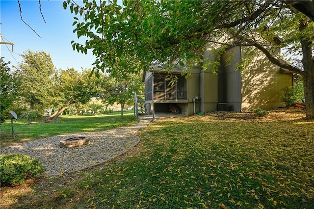 view of yard featuring a fire pit and a sunroom