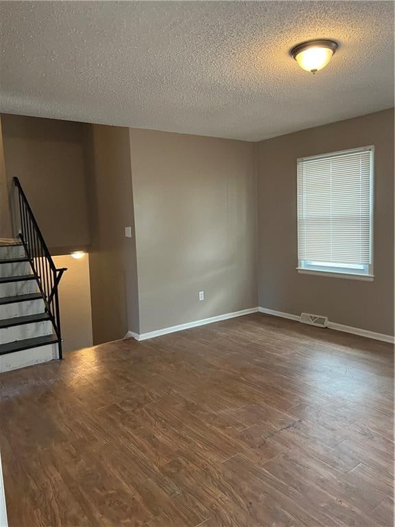 spare room with a textured ceiling and dark hardwood / wood-style flooring