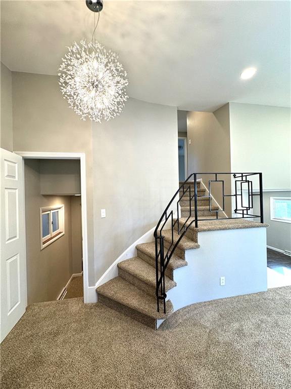 stairway with a notable chandelier and carpet flooring