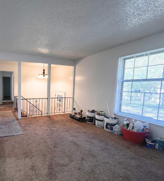 unfurnished room featuring a textured ceiling, a notable chandelier, and carpet flooring