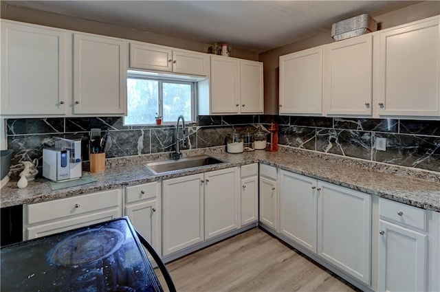 kitchen featuring decorative backsplash, sink, white cabinets, and light hardwood / wood-style flooring