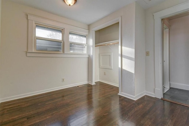 unfurnished bedroom featuring a closet and dark wood-type flooring