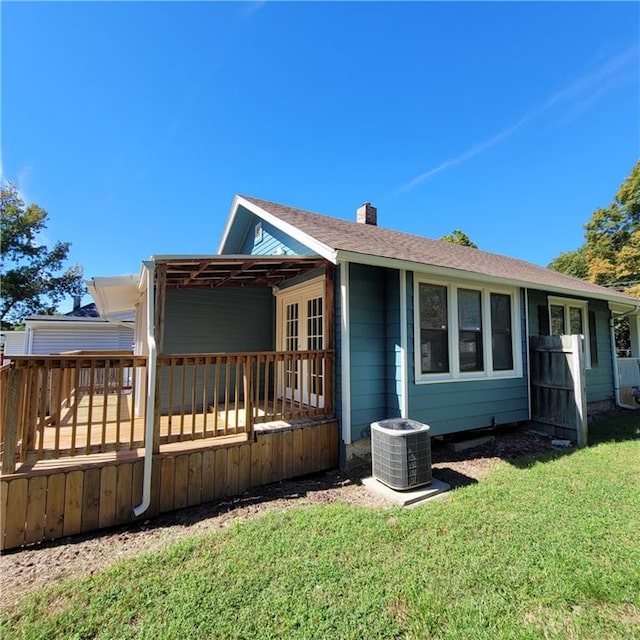 rear view of property featuring a lawn, a deck, and central air condition unit