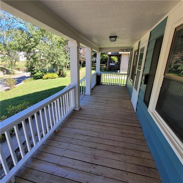 wooden terrace with a lawn and a porch