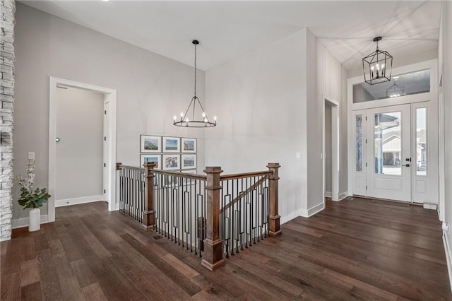 entrance foyer with an inviting chandelier, a towering ceiling, and dark hardwood / wood-style floors