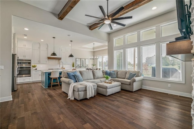 living room with ceiling fan with notable chandelier, a wealth of natural light, beamed ceiling, and dark wood-type flooring