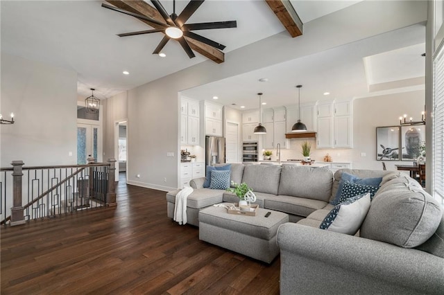 living room with sink, ceiling fan with notable chandelier, beam ceiling, and dark wood-type flooring