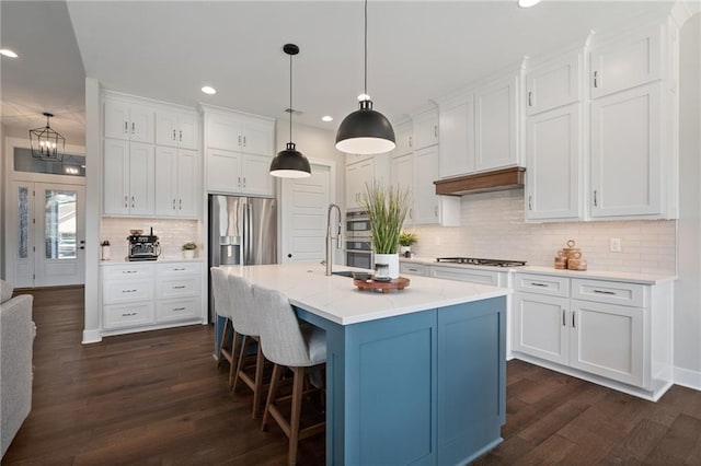 kitchen featuring white cabinetry, dark wood-type flooring, an island with sink, backsplash, and pendant lighting