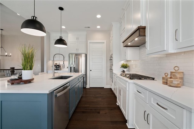 kitchen featuring dark wood-type flooring, an island with sink, white cabinetry, stainless steel appliances, and decorative light fixtures