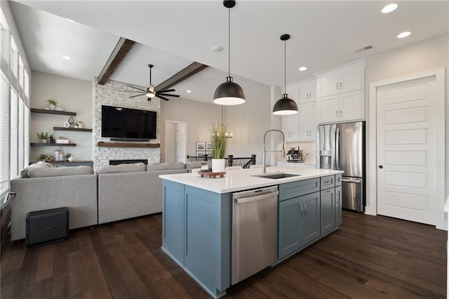 kitchen with an island with sink, sink, white cabinetry, stainless steel appliances, and a wealth of natural light