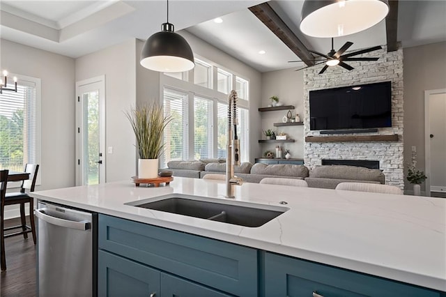 kitchen featuring dishwasher, light stone counters, dark hardwood / wood-style floors, sink, and a stone fireplace