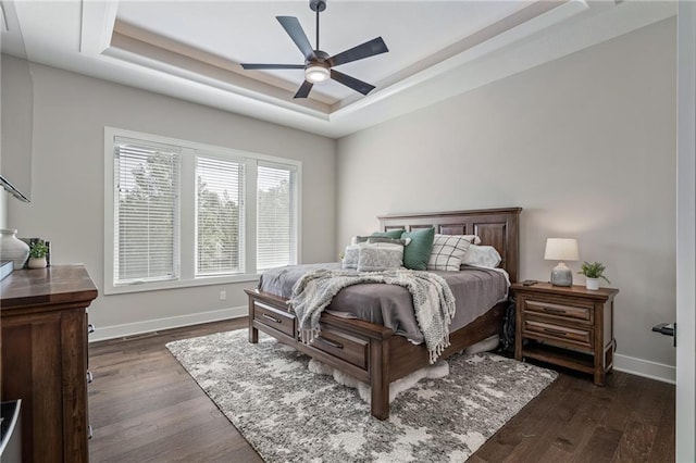 bedroom with a tray ceiling, ceiling fan, and dark hardwood / wood-style flooring