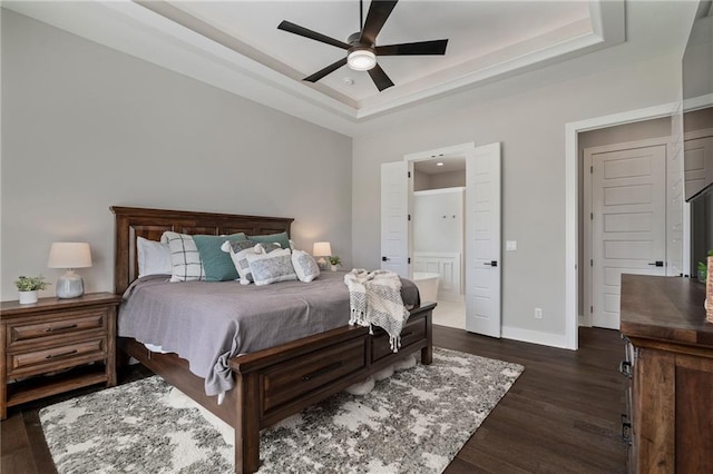 bedroom featuring connected bathroom, ceiling fan, a raised ceiling, and dark hardwood / wood-style flooring