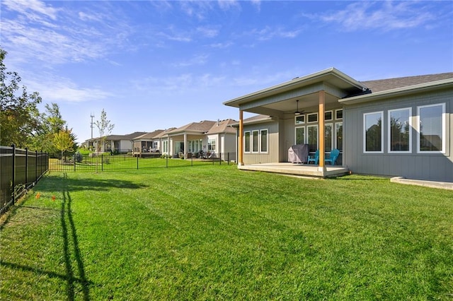 rear view of property with ceiling fan, a yard, and a patio area