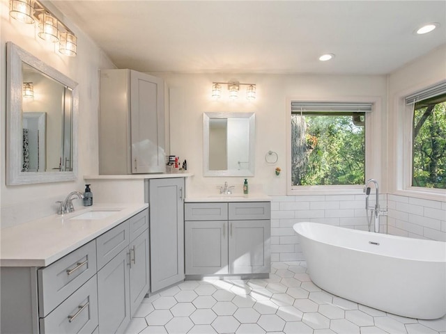 bathroom featuring a bathtub, a healthy amount of sunlight, tile walls, and vanity