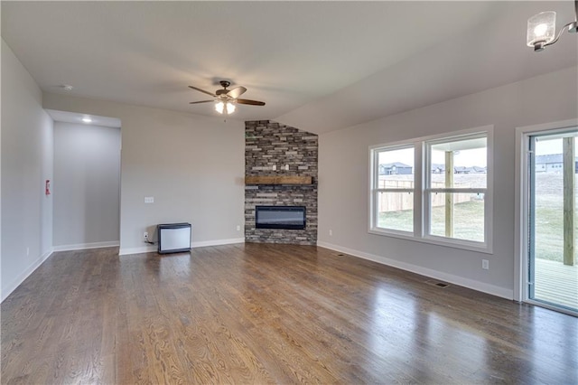 unfurnished living room featuring ceiling fan, a fireplace, wood finished floors, baseboards, and vaulted ceiling