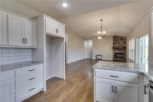 kitchen with backsplash, an inviting chandelier, white cabinets, vaulted ceiling, and wood finished floors