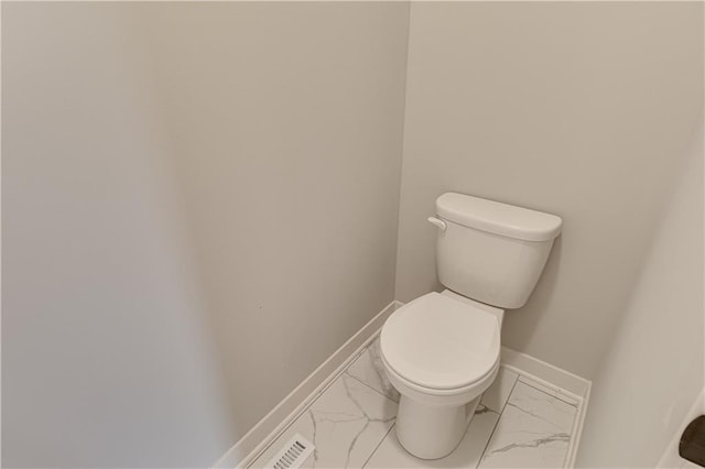 bathroom featuring marble finish floor, toilet, and baseboards