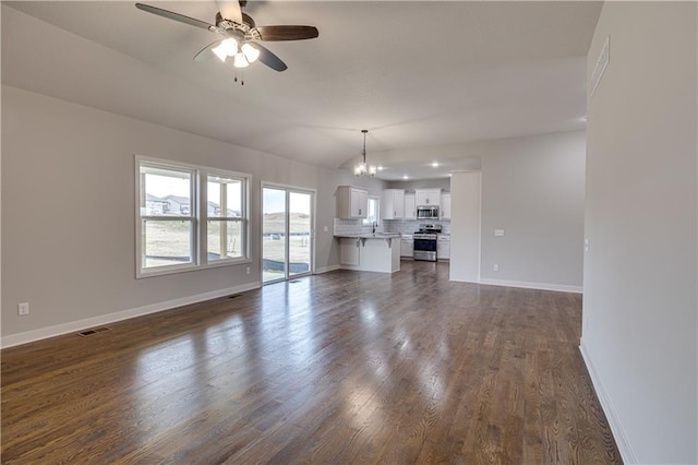 unfurnished living room featuring dark wood-style floors, visible vents, a sink, baseboards, and ceiling fan with notable chandelier