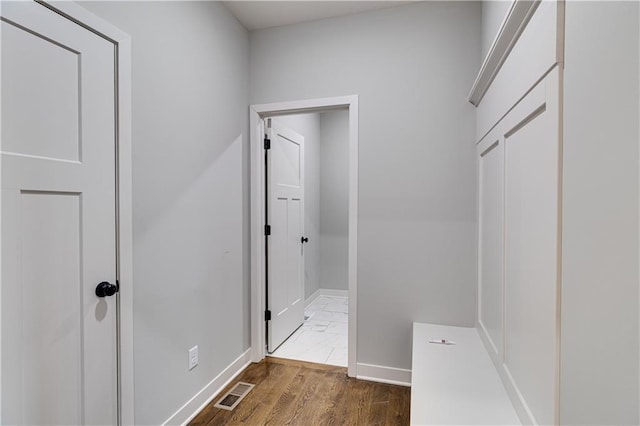 hallway with visible vents, baseboards, and dark wood-type flooring