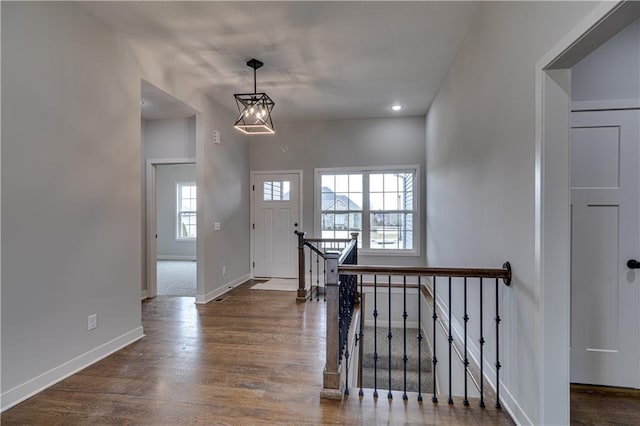 foyer entrance featuring dark wood-type flooring, a notable chandelier, and baseboards