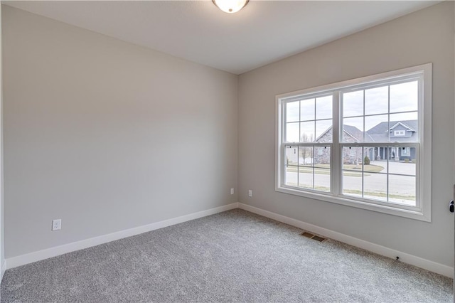 carpeted empty room featuring visible vents, plenty of natural light, and baseboards